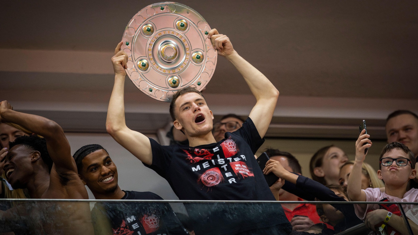 One of the 2024 Bundesliga-winning side lifts the trophy aloft.