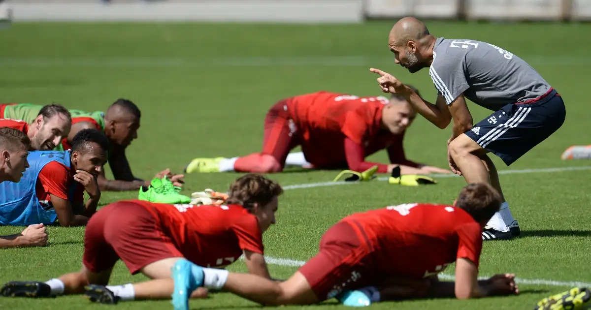 Head coach Pep Guardiola (R) talks to Joshua Kimmich (L) and Julian Green (3 L) as other team-members stretch on the ground during a training session in Munich, Germany, 27 July 2015.